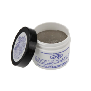 Open white container of JB Bore cleaning paste with blue text on the label, next to a black lid leaning against it.